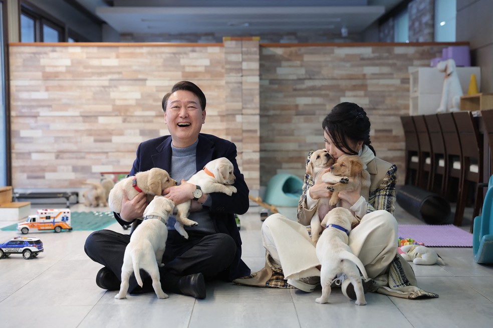 O presidente Yoon Suk-yeol e a primeira-dama Kim Keon-hee posam com filhotes de cachorro na Samsung Guide Dog School em Yongin. — Foto: South Korean Presidential Office / AFP