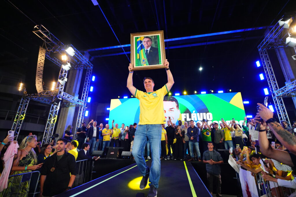 Flávio Bolsonaro segura imagem do pai em evento no Rio (Vittor Sales/Divulgação pré-campanha)
